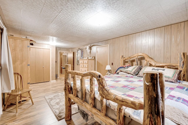 bedroom with light wood finished floors and wood walls