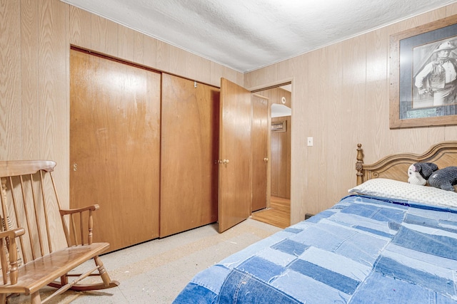 bedroom with a textured ceiling, wood walls, and a closet