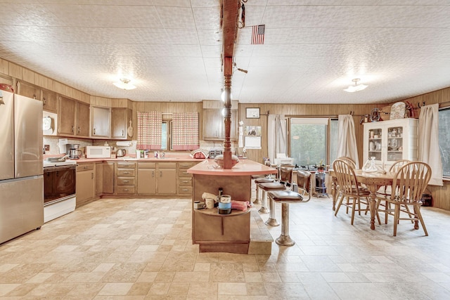 kitchen with light countertops, white appliances, a sink, and wooden walls