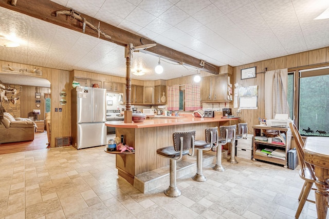 kitchen with light countertops, range with electric cooktop, freestanding refrigerator, and wooden walls