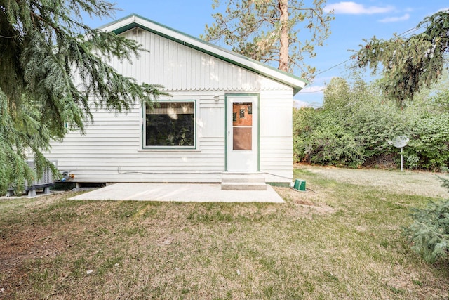 rear view of property featuring entry steps, a yard, and a patio