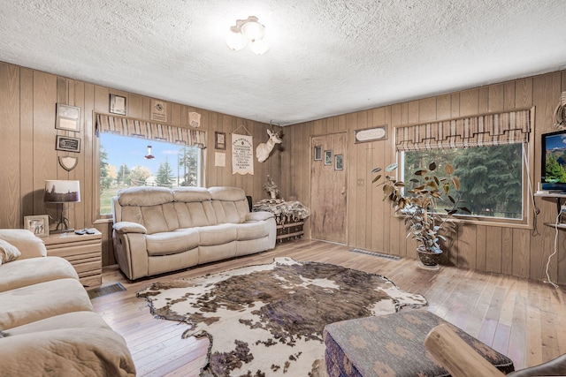 living area featuring a textured ceiling, wood walls, and wood-type flooring