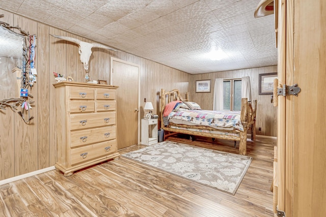 bedroom with wooden walls, wood finished floors, and baseboards