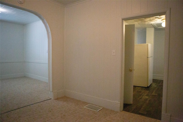 unfurnished room featuring baseboards, visible vents, arched walkways, crown molding, and carpet floors