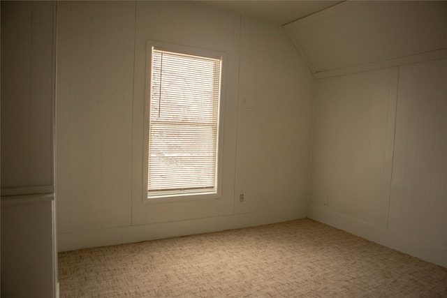 empty room featuring vaulted ceiling and carpet flooring