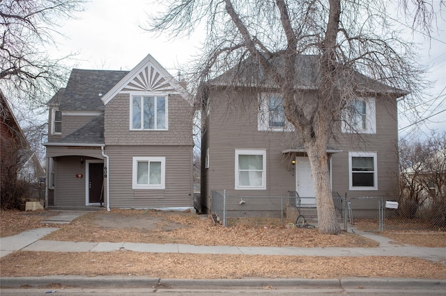 view of front facade featuring roof with shingles and a fenced front yard