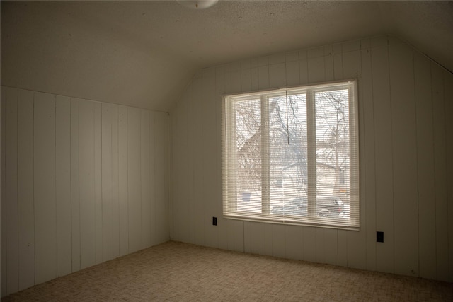 bonus room featuring carpet floors, lofted ceiling, and wood walls