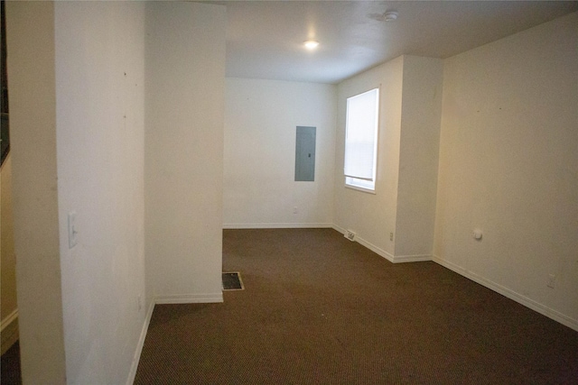 empty room featuring baseboards, dark colored carpet, visible vents, and electric panel