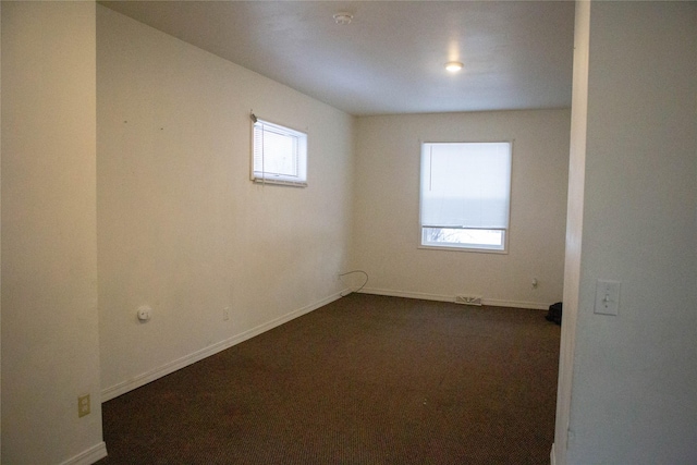 unfurnished room with dark carpet and baseboards