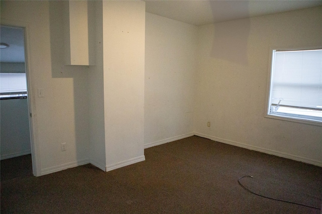 unfurnished room featuring dark colored carpet and baseboards