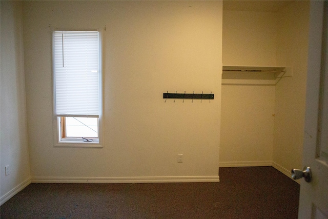 interior space featuring dark colored carpet and baseboards