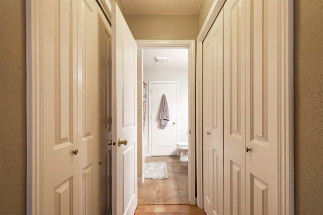 hall with light tile patterned floors and a textured wall