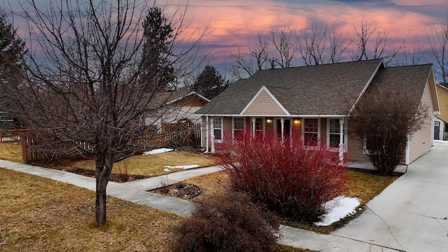 view of front of property featuring roof with shingles, a porch, and a yard