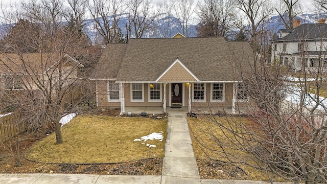 new england style home featuring a shingled roof and a front yard