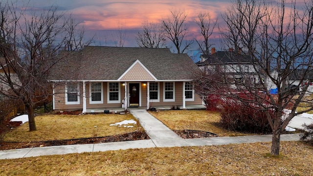 view of front of house with a porch, a front lawn, and a shingled roof