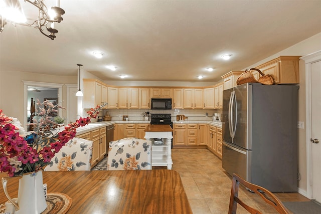 kitchen featuring black appliances, tasteful backsplash, light countertops, and decorative light fixtures