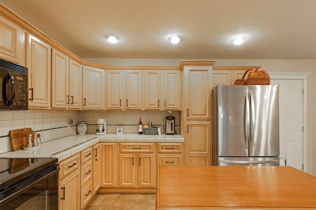 kitchen with tile countertops, black appliances, and decorative backsplash