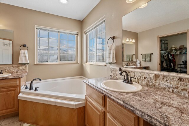 5331 Fiddler Ct, Florence, MT 59833 - bathroom featuring two vanities, a garden tub, a walk in closet, and tile patterned floors
