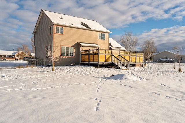 snow covered house with stairs, fence, and a wooden deck