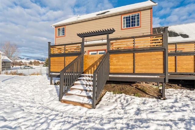 snow covered back of property with stairway and a wooden deck