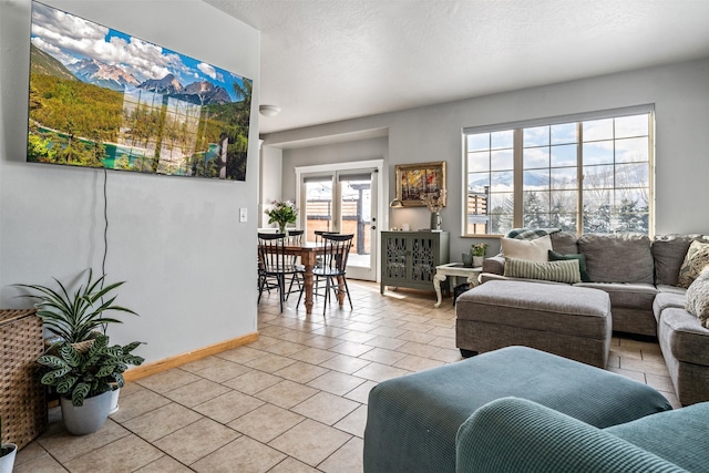 living area featuring baseboards, a textured ceiling, and light tile patterned flooring