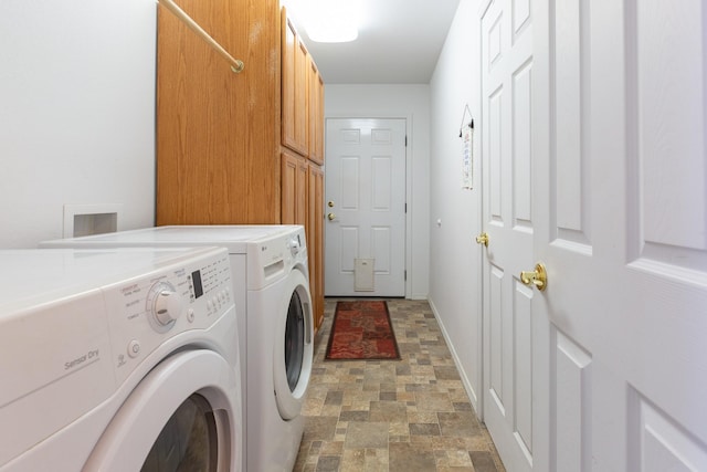 clothes washing area with stone finish floor, washer and clothes dryer, cabinet space, and baseboards