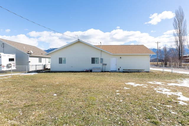 rear view of property featuring a yard and fence