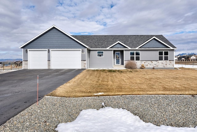 ranch-style home with a garage, stone siding, aphalt driveway, and a front yard