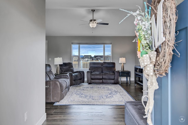 living room with a ceiling fan, baseboards, and wood finished floors