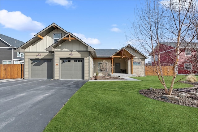 view of front of house with aphalt driveway, an attached garage, fence, a front lawn, and board and batten siding