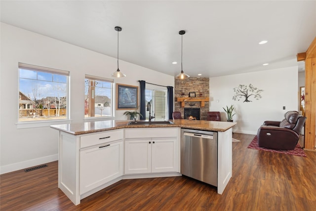 kitchen featuring a stone fireplace, a sink, visible vents, open floor plan, and stainless steel dishwasher