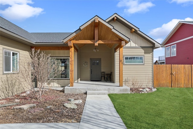 view of front of home featuring covered porch, board and batten siding, a front yard, and fence