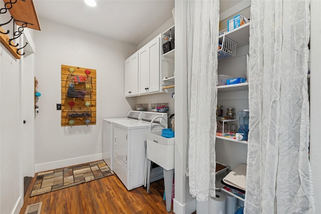 laundry room with cabinet space, baseboards, visible vents, dark wood finished floors, and washing machine and clothes dryer