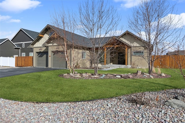 view of front facade with aphalt driveway, an attached garage, fence, board and batten siding, and a front yard