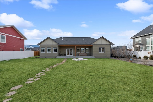 back of house featuring board and batten siding, a fenced backyard, a lawn, and a patio