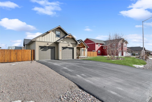 view of front of property featuring a garage, fence, aphalt driveway, and board and batten siding