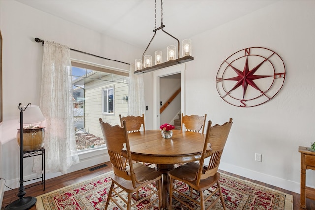 dining room featuring stairs, visible vents, baseboards, and wood finished floors