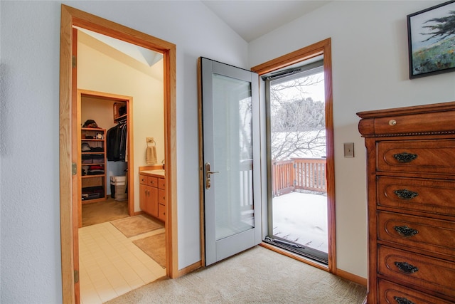 foyer with light carpet, baseboards, and vaulted ceiling