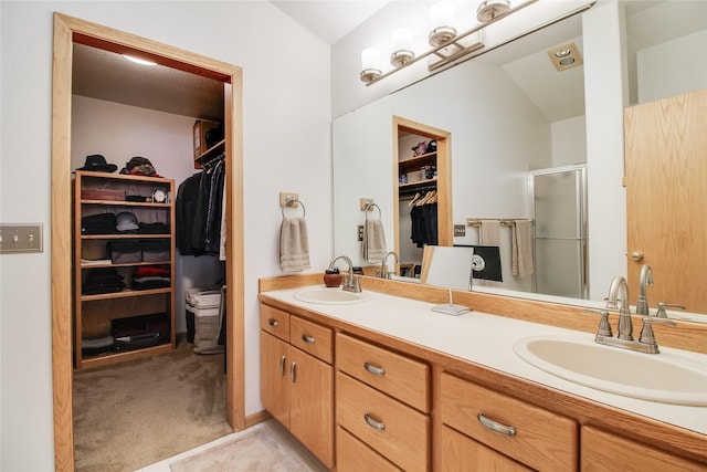 bathroom featuring double vanity, a stall shower, a walk in closet, and a sink