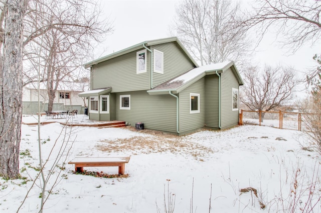 snow covered property with entry steps and fence