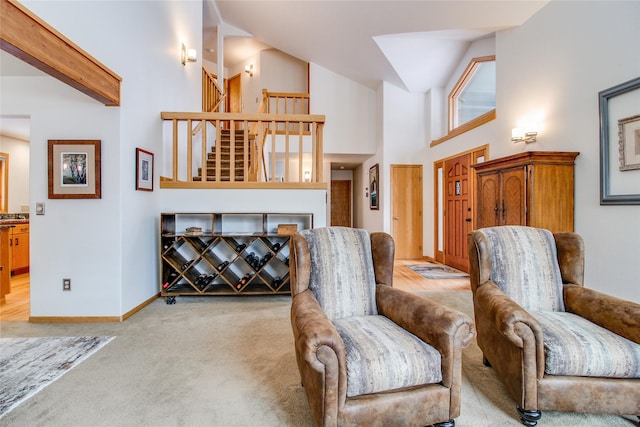 living area featuring high vaulted ceiling, light colored carpet, stairway, and baseboards