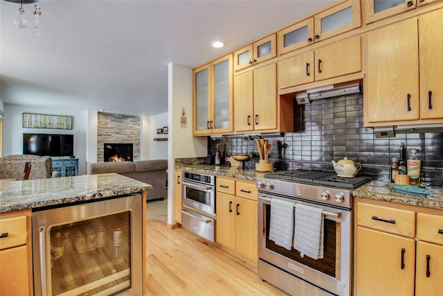 kitchen featuring beverage cooler, appliances with stainless steel finishes, under cabinet range hood, backsplash, and a warming drawer