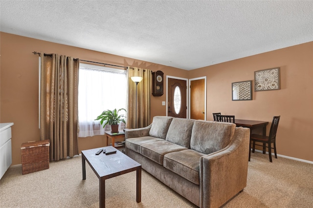 living area featuring light carpet, baseboards, and a textured ceiling