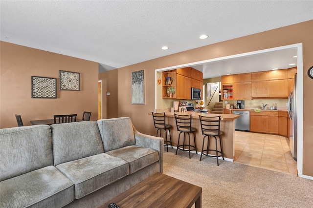 living room with light tile patterned floors, a textured ceiling, recessed lighting, light colored carpet, and stairs