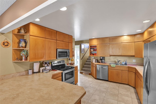 kitchen featuring stainless steel appliances, light countertops, open shelves, a sink, and recessed lighting