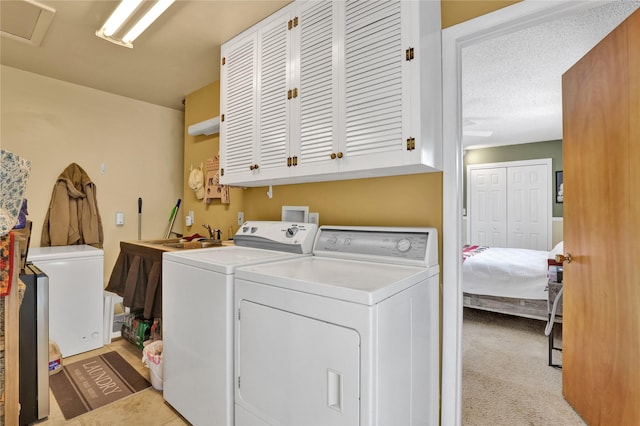 laundry room with a textured ceiling, light colored carpet, a sink, washer and dryer, and cabinet space