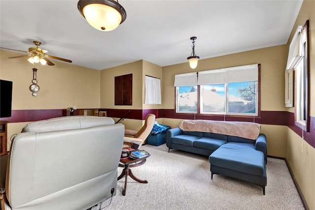 carpeted living area with a ceiling fan