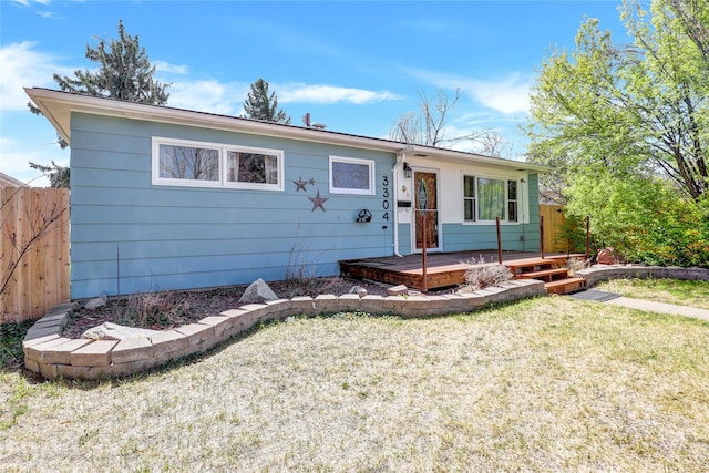 single story home featuring fence, a front lawn, and a deck