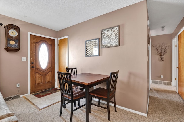 dining space featuring baseboards, visible vents, a textured ceiling, and light colored carpet