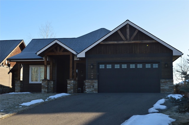 craftsman-style house with a garage, driveway, board and batten siding, and stone siding